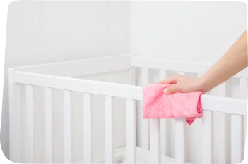 A staff member carefully sanitizing a crib using non-toxic cleaning products, demonstrating adherence to UAE and UK childcare standards for safety and hygiene.