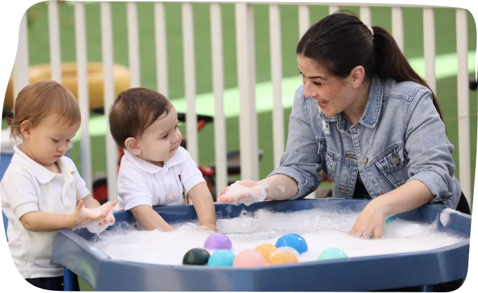 Babies participating in small world play with water and colorful balls at Step By Step Nursery Dubai, promoting sensory exploration.