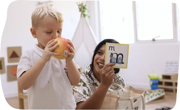 Foundation-aged child learning phonics, reading, and mark-making with a caregiver at Step by Step nursery Dubai, developing early literacy skills.