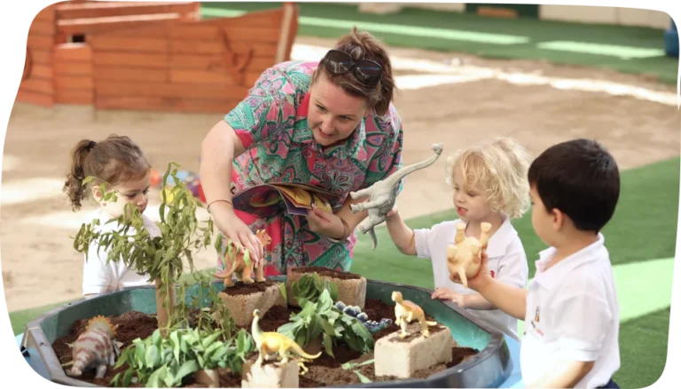 Nursery-aged children exploring small world play with a teacher at Step By Step Nursery Dubai, fostering imagination and creativity.