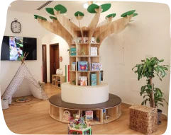 Classroom facility at Kids Academy Nursery, featuring a creative tree-shaped bookshelf with children's books, a cozy teepee, and welcoming decor